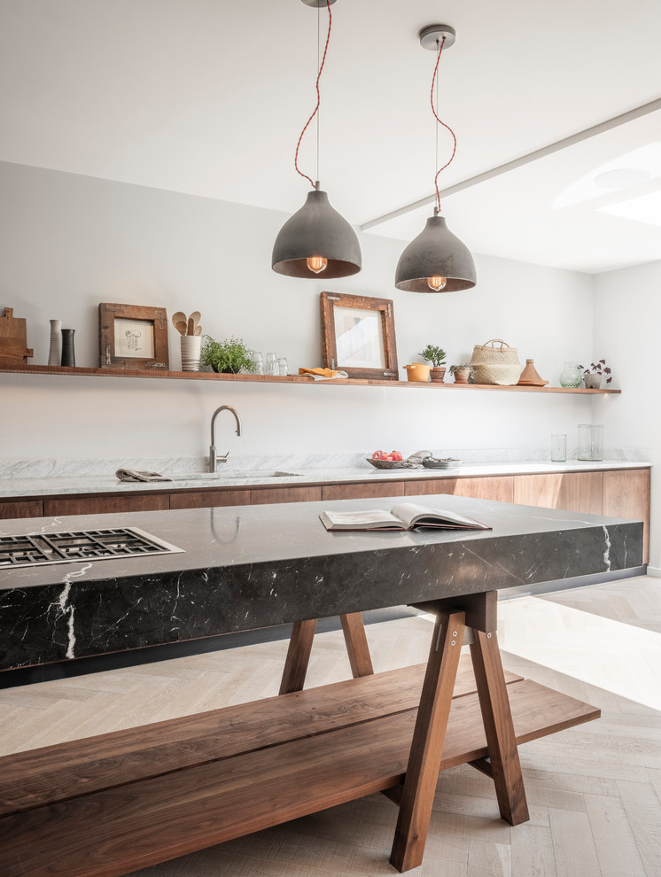 This is an example of a large contemporary single-wall open plan kitchen in London with an integrated sink, flat-panel cabinets, dark wood cabinets, marble benchtops, stainless steel appliances, medium hardwood floors, with island and white benchtop.