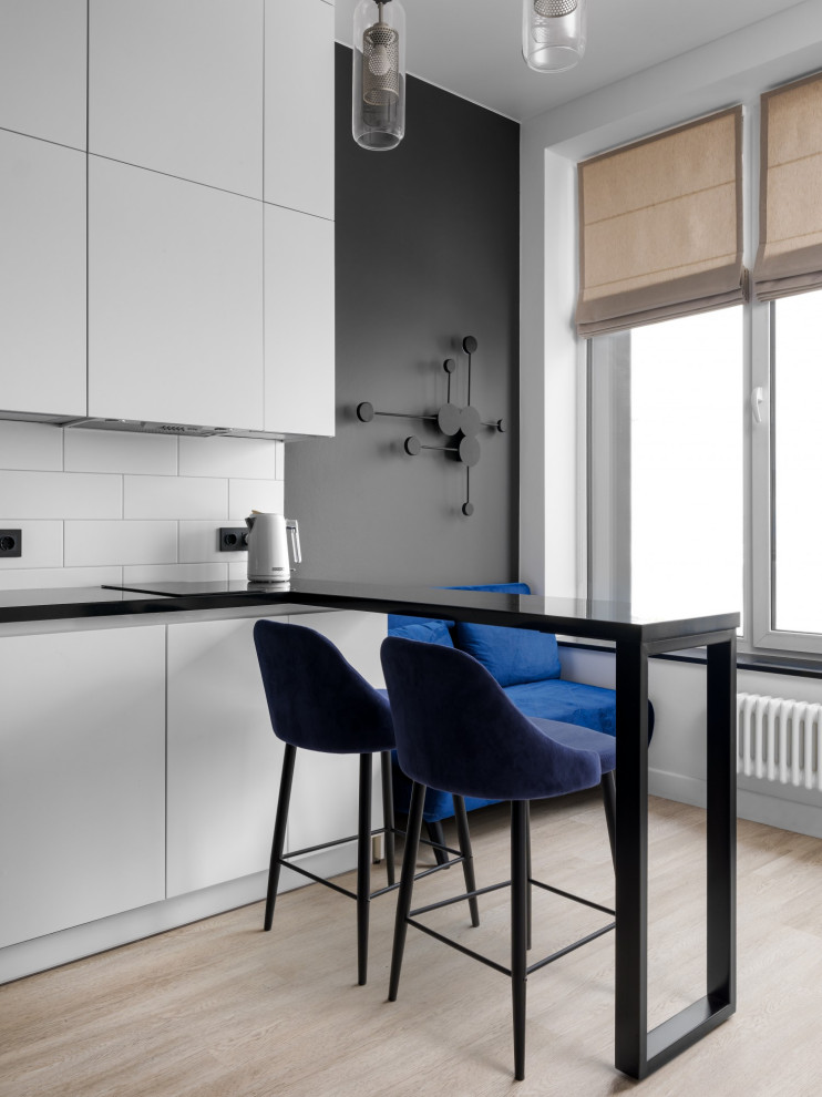 Design ideas for a small contemporary galley open plan kitchen in Other with an undermount sink, flat-panel cabinets, white cabinets, quartz benchtops, white splashback, black appliances, laminate floors, no island, beige floor and black benchtop.
