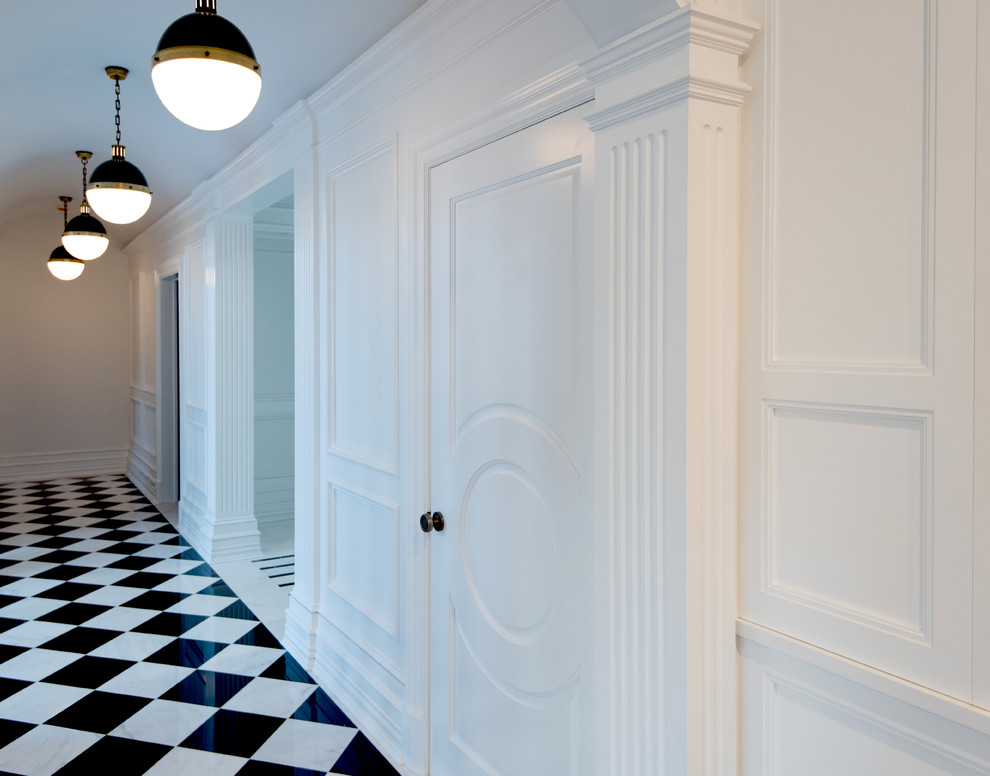 This is an example of a large traditional hallway in New York with white walls and marble floors.