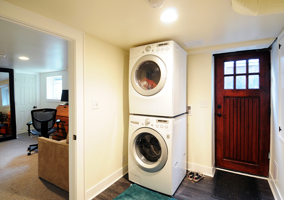 This is an example of a mid-sized modern laundry room in Seattle with white walls, linoleum floors and a stacked washer and dryer.