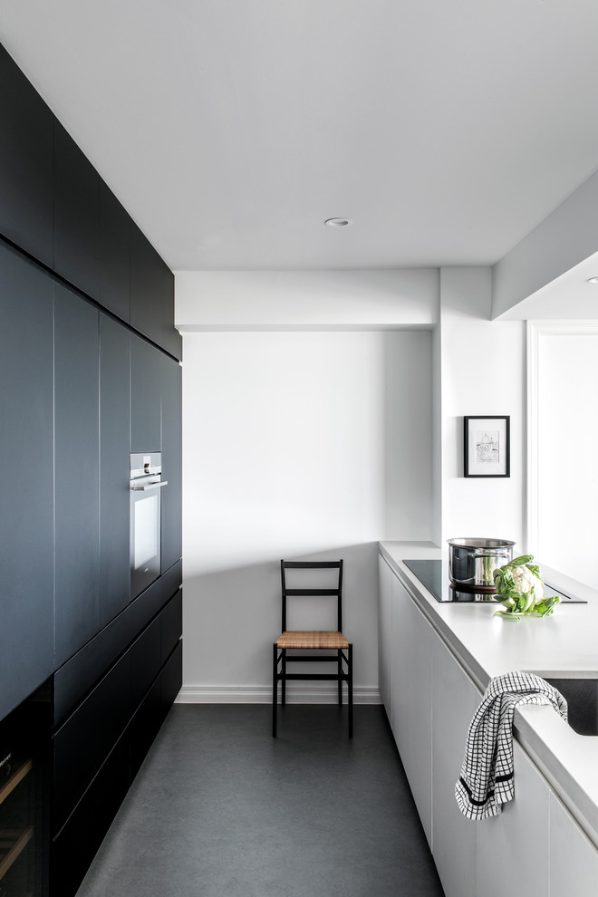 Inspiration for a small galley open plan kitchen in Other with an undermount sink, flat-panel cabinets, black cabinets, quartz benchtops, panelled appliances, linoleum floors, grey floor and white benchtop.