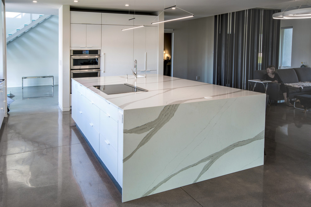 Photo of a large modern kitchen in Denver with solid surface benchtops, concrete floors, with island and white benchtop.