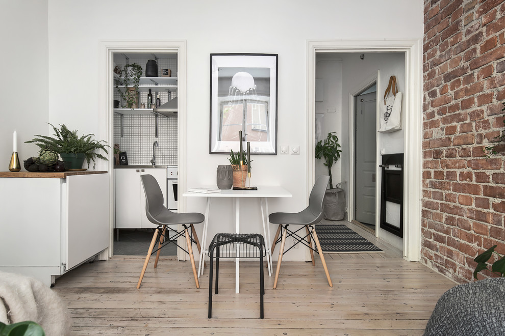 Photo of a small scandinavian dining room in Stockholm with white walls and light hardwood floors.