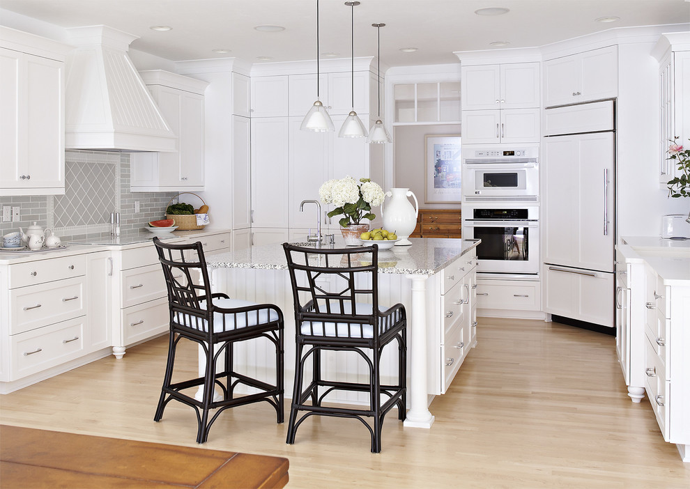 Design ideas for a beach style u-shaped kitchen in Milwaukee with shaker cabinets, white cabinets, grey splashback, panelled appliances, light hardwood floors and with island.