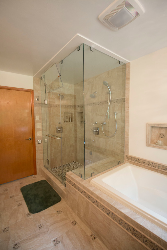 Example of a mid-sized transitional master beige tile and ceramic tile ceramic tile drop-in bathtub design with an undermount sink, flat-panel cabinets, light wood cabinets, solid surface countertops, a two-piece toilet and beige walls