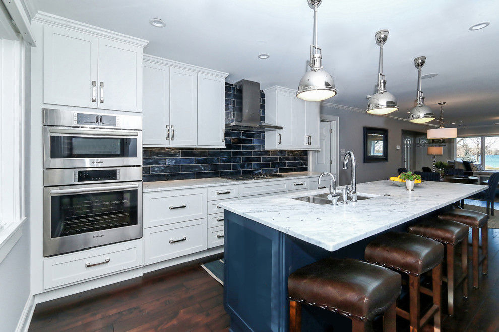 Mid-sized transitional single-wall medium tone wood floor eat-in kitchen photo in Minneapolis with an undermount sink, shaker cabinets, blue cabinets, marble countertops, blue backsplash, glass tile backsplash, stainless steel appliances and an island