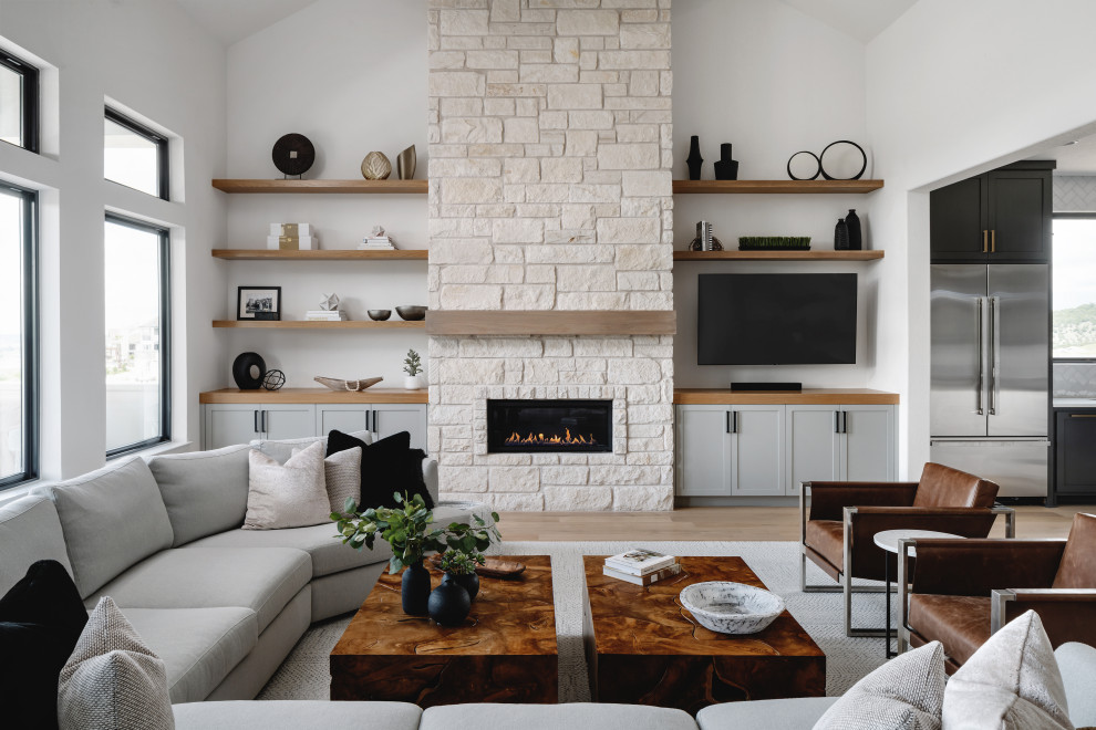 オースティンにあるトランジショナルスタイルのおしゃれなLDK (茶色い壁、無垢フローリング、横長型暖炉、石材の暖炉まわり、壁掛け型テレビ、茶色い床) の写真