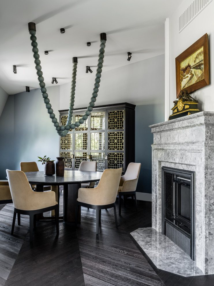 Inspiration for a transitional dining room in London with blue walls, dark hardwood floors, a standard fireplace and black floor.