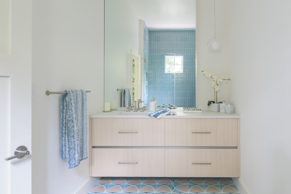 Свежая идея для дизайна: детская ванная комната среднего размера в стиле модернизм с плоскими фасадами, бежевыми фасадами, ванной в нише, душем над ванной, унитазом-моноблоком, синей плиткой, керамогранитной плиткой, белыми стенами, полом из цементной плитки, врезной раковиной, столешницей из искусственного кварца, синим полом, душем с распашными дверями, белой столешницей, сиденьем для душа, тумбой под одну раковину и подвесной тумбой - отличное фото интерьера