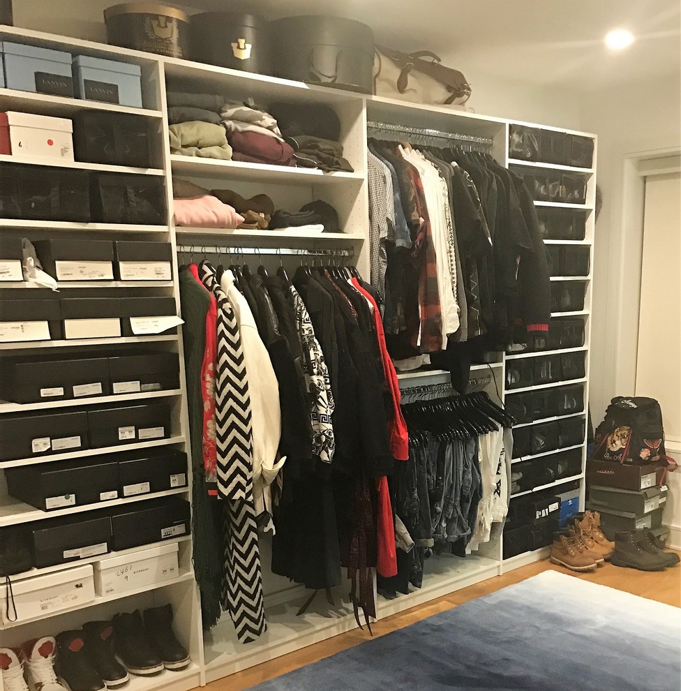 This is an example of a transitional men's dressing room in New York with open cabinets, white cabinets and medium hardwood floors.