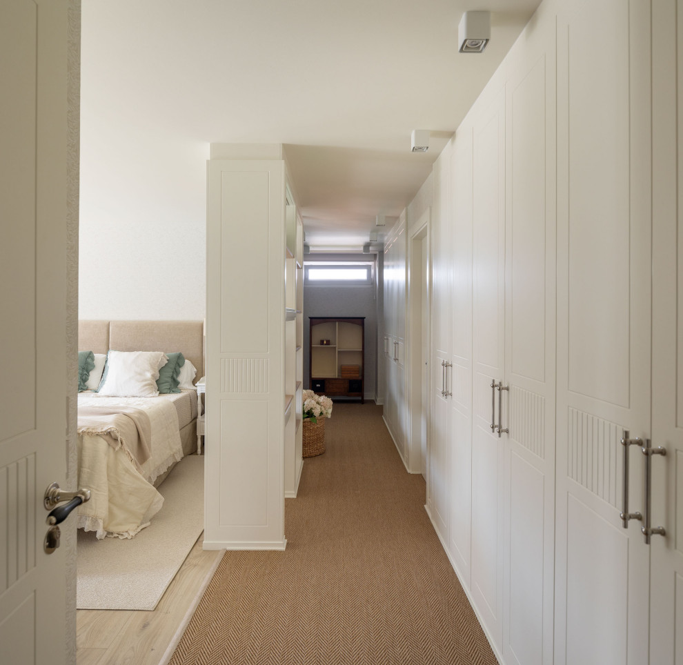 Inspiration pour un grand dressing room traditionnel neutre avec un placard avec porte à panneau surélevé, des portes de placard blanches, moquette et un sol blanc.