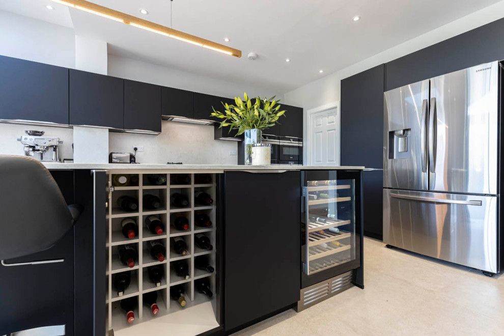 Photo of a large modern galley open plan kitchen in Hertfordshire with a single-bowl sink, flat-panel cabinets, black cabinets, concrete benchtops, white splashback, black appliances, ceramic floors, with island, grey floor and white benchtop.