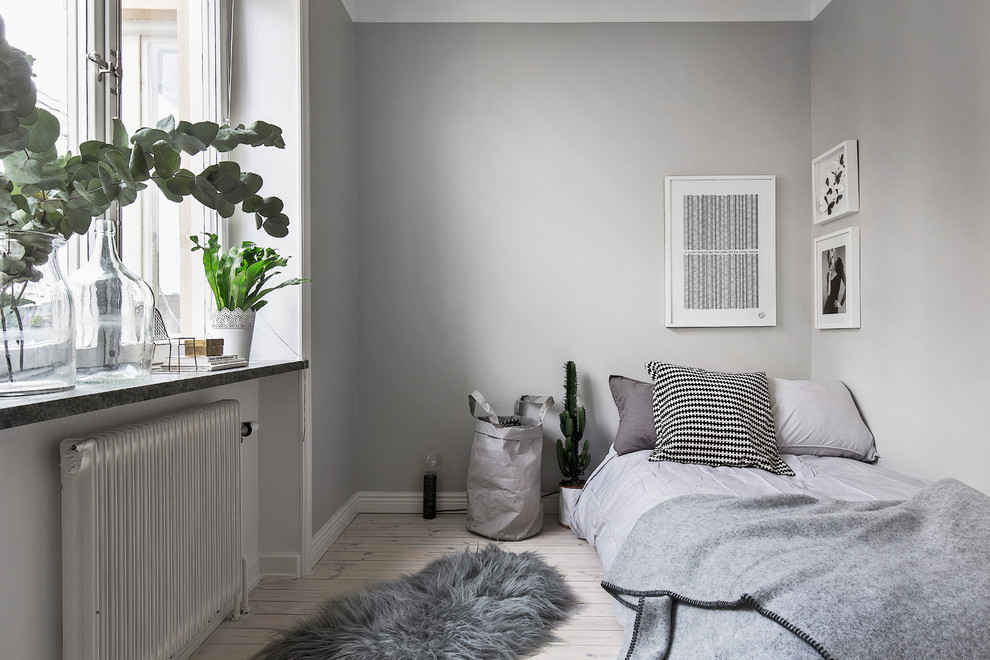 Design ideas for a small scandinavian guest bedroom in Stockholm with grey walls, light hardwood floors and no fireplace.