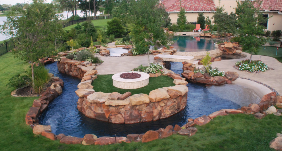 This is an example of a large tropical backyard custom-shaped pool in Houston with a hot tub.