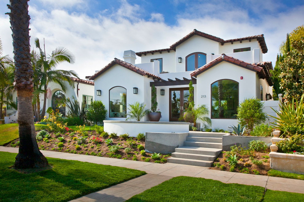 Photo of a large mediterranean two-storey white house exterior in Los Angeles with stone veneer, a gable roof and a tile roof.