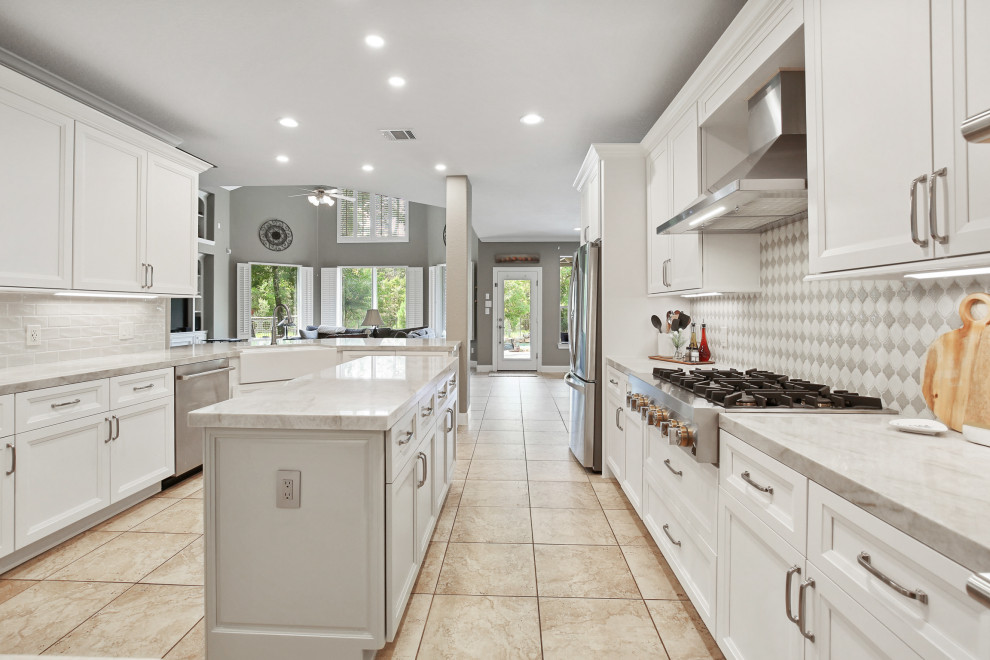Exempel på ett mellanstort klassiskt brun brunt kök, med en rustik diskho, luckor med infälld panel, vita skåp, bänkskiva i kvartsit, vitt stänkskydd, stänkskydd i keramik, rostfria vitvaror och en köksö