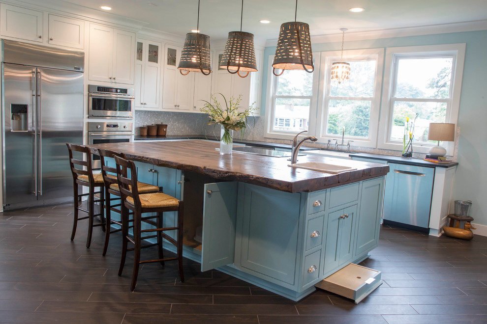 Inspiration for a large beach style l-shaped open plan kitchen in Other with a farmhouse sink, beaded inset cabinets, blue cabinets, stainless steel appliances, dark hardwood floors, with island, soapstone benchtops, grey splashback, mosaic tile splashback, brown floor and black benchtop.