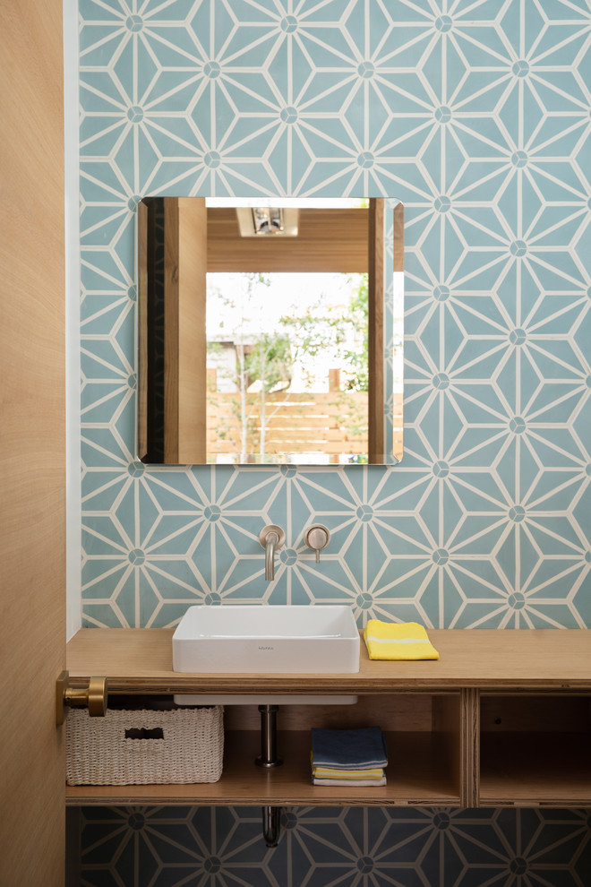 Design ideas for a midcentury powder room in Denver with open cabinets, light wood cabinets, blue tile, multi-coloured tile, white tile, a vessel sink and wood benchtops.