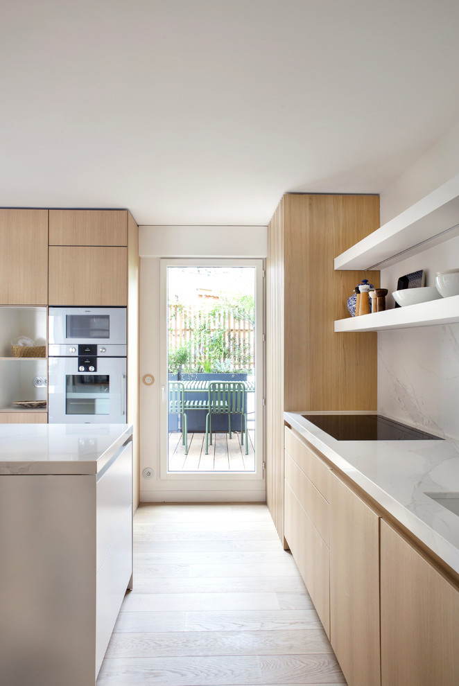 Mid-sized contemporary u-shaped open plan kitchen in Paris with an integrated sink, beaded inset cabinets, quartzite benchtops, white splashback, marble splashback, stainless steel appliances, light hardwood floors, with island and white benchtop.