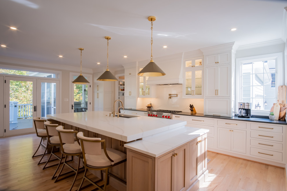 This is an example of a large traditional l-shaped eat-in kitchen in DC Metro with an undermount sink, beaded inset cabinets, light wood cabinets, soapstone benchtops, white splashback, engineered quartz splashback, stainless steel appliances, light hardwood floors, with island, brown floor, black benchtop and wallpaper.