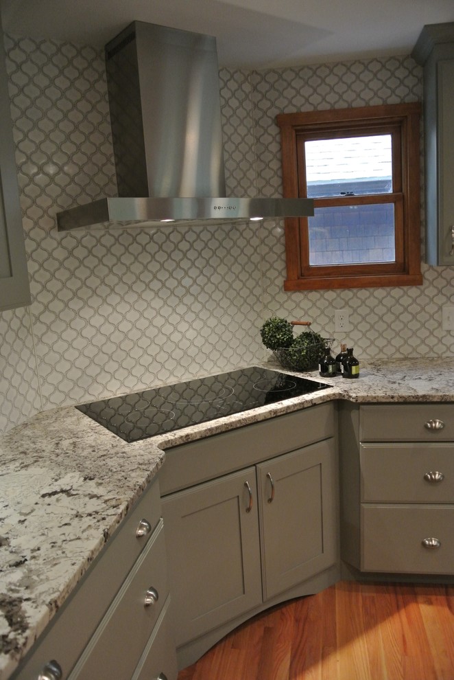 Inspiration for a large transitional l-shaped light wood floor eat-in kitchen remodel in Boston with a farmhouse sink, shaker cabinets, gray cabinets, granite countertops, white backsplash, ceramic backsplash, stainless steel appliances, an island and gray countertops