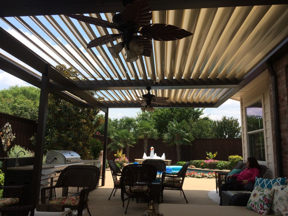 This is an example of a mid-sized contemporary backyard patio in Dallas with an outdoor kitchen, concrete slab and a pergola.