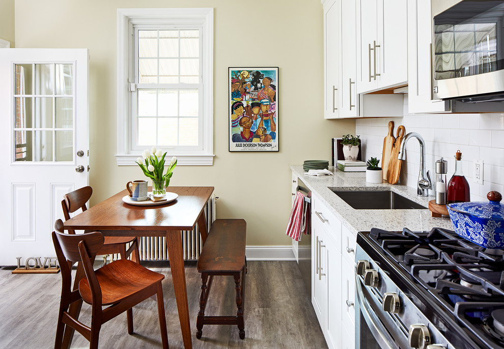 Inspiration for a timeless single-wall brown floor eat-in kitchen remodel in DC Metro with an undermount sink, shaker cabinets, white cabinets, white backsplash, subway tile backsplash, stainless steel appliances, no island and multicolored countertops