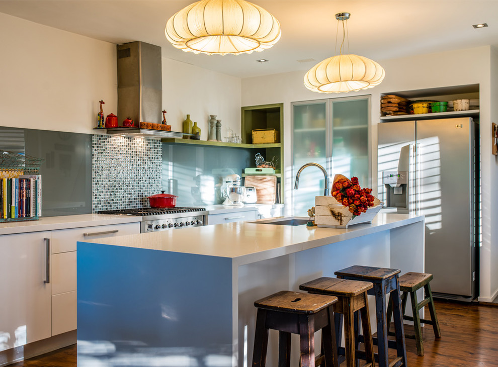 Photo of an eclectic galley kitchen in Sydney with an undermount sink, flat-panel cabinets, white cabinets, grey splashback, glass sheet splashback, stainless steel appliances, dark hardwood floors, with island and brown floor.