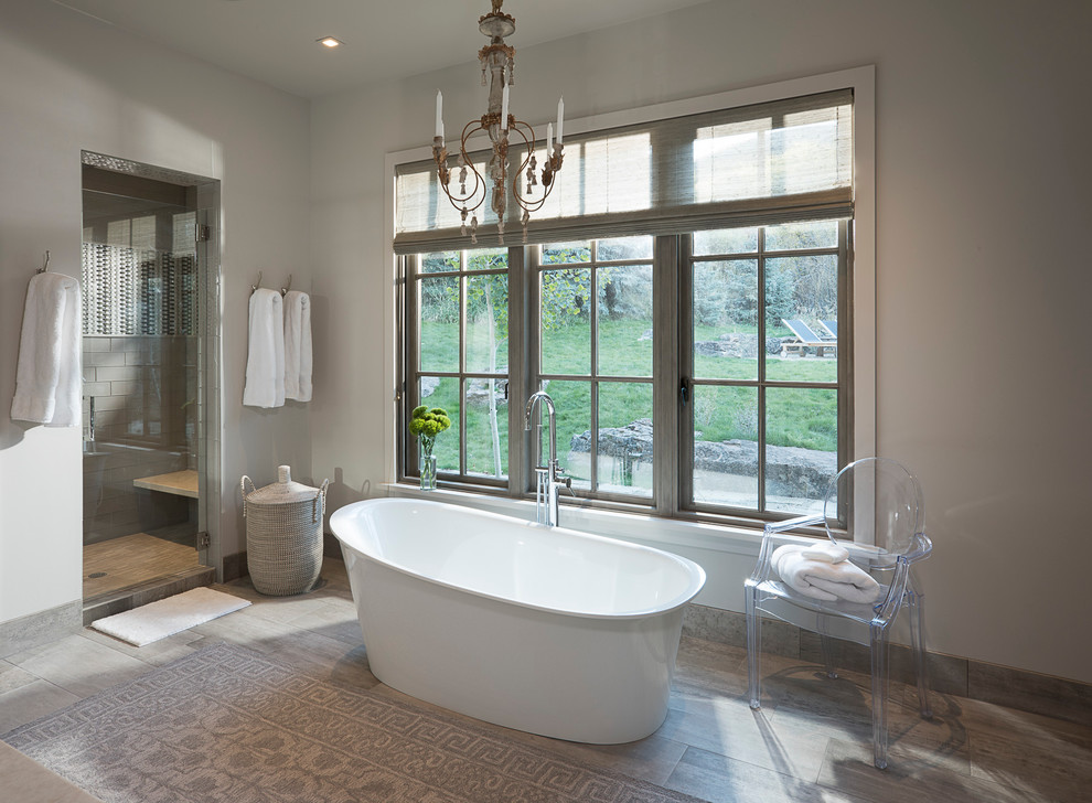 This is an example of a transitional bathroom in Other with a freestanding tub and grey walls.