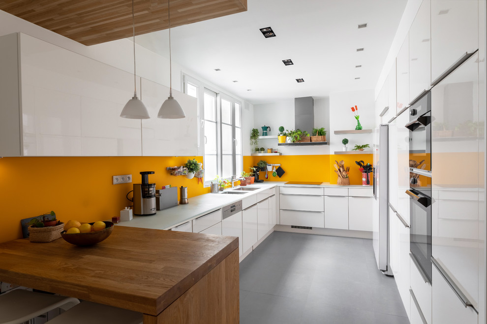 Inspiration for a mid-sized contemporary l-shaped separate kitchen in Paris with a double-bowl sink, flat-panel cabinets, white cabinets, glass benchtops, yellow splashback, glass tile splashback, panelled appliances, ceramic floors, no island, grey floor and white benchtop.