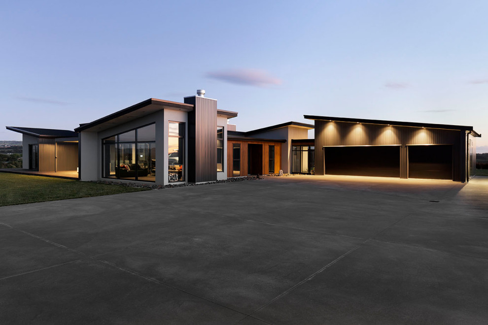 Cette image montre une grande façade de maison multicolore design de plain-pied avec un revêtement mixte, un toit papillon, un toit en métal et un toit noir.