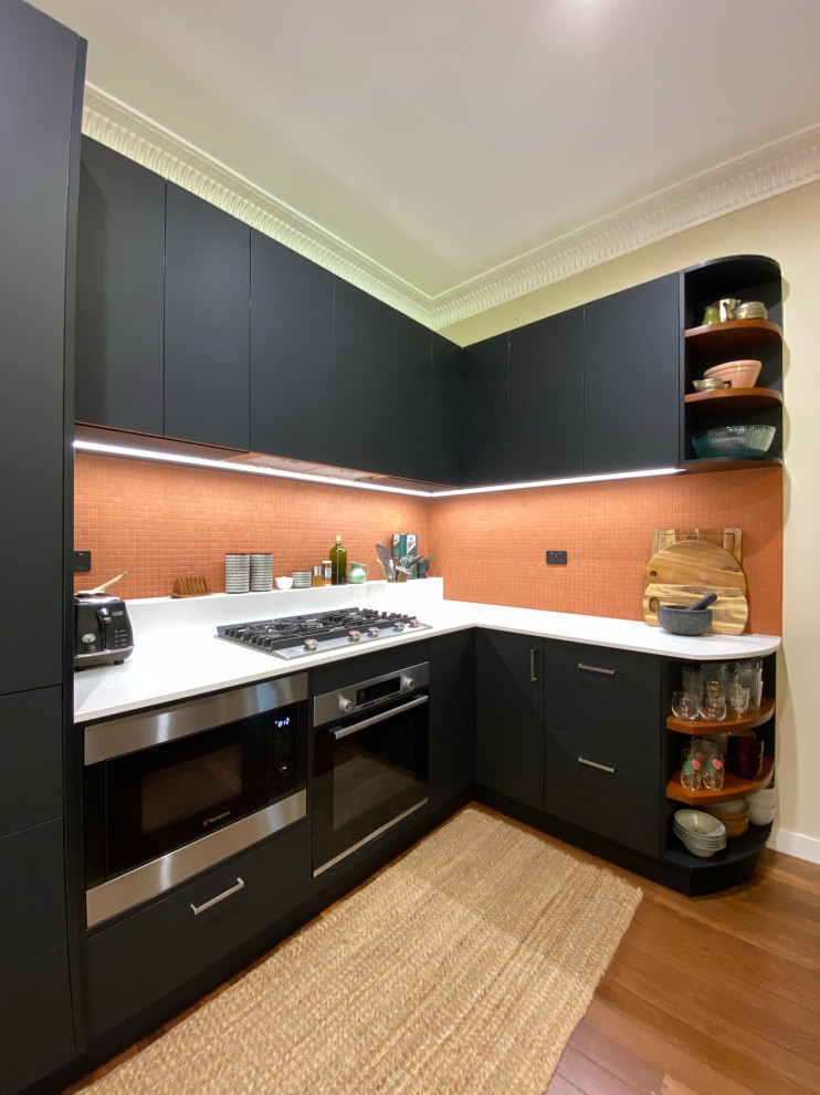 Exempel på ett litet modernt vit vitt kök, med släta luckor, svarta skåp, bänkskiva i kvarts, orange stänkskydd, stänkskydd i terrakottakakel, svarta vitvaror, mellanmörkt trägolv, brunt golv och en enkel diskho