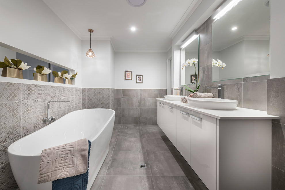 This is an example of a contemporary bathroom in Perth with white cabinets, a freestanding tub, gray tile, white walls, ceramic floors and grey floor.