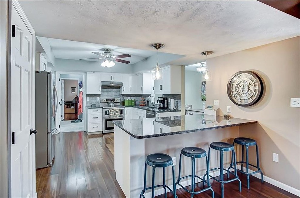 Example of a transitional medium tone wood floor kitchen design with shaker cabinets, white cabinets and granite countertops