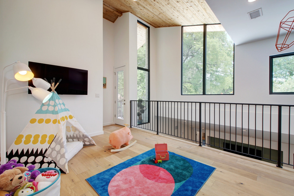 Inredning av ett minimalistiskt stort loftrum, med vita väggar, ljust trägolv, en väggmonterad TV och brunt golv