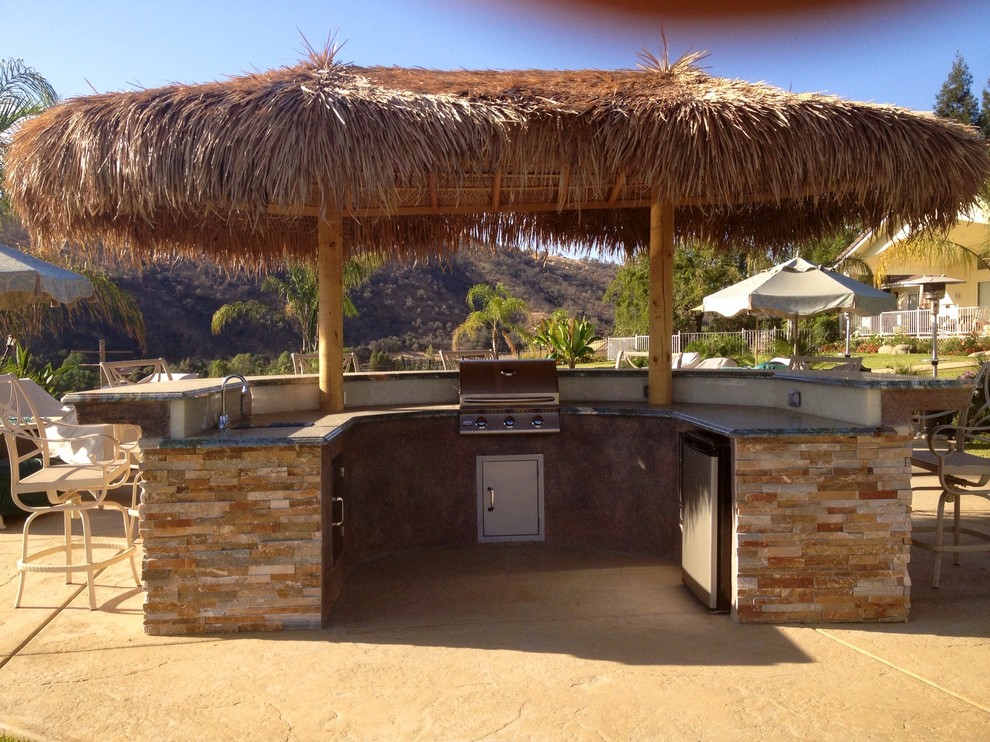 Photo of a large tropical backyard patio in Orange County with an outdoor kitchen, stamped concrete and a gazebo/cabana.