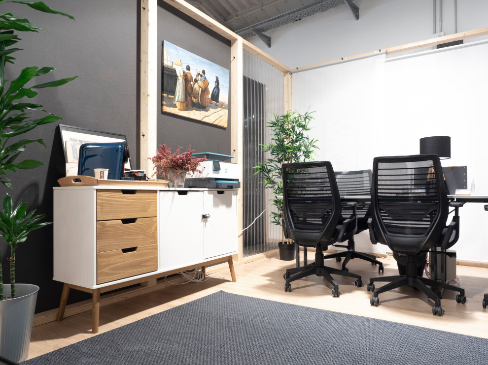 Geräumiges Industrial Arbeitszimmer mit Arbeitsplatz, grauer Wandfarbe, hellem Holzboden, freistehendem Schreibtisch und beigem Boden in Barcelona