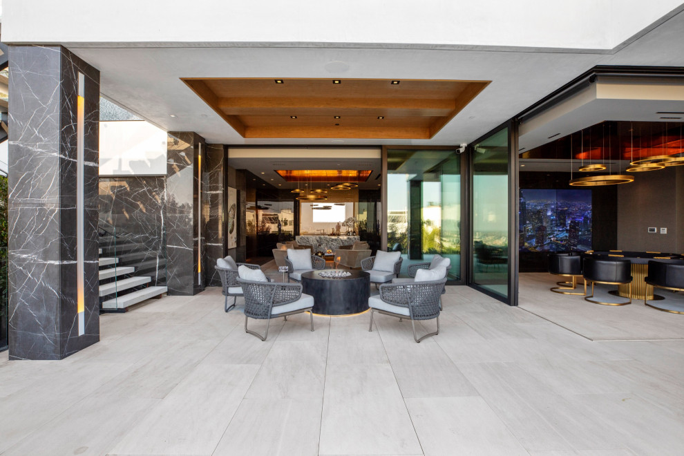 This is an example of a large contemporary courtyard patio in Los Angeles with a fire feature and a roof extension.