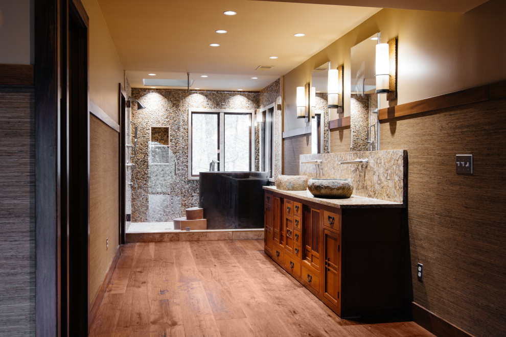 Design ideas for a modern master bathroom in Nashville with furniture-like cabinets, medium wood cabinets, a japanese tub, a shower/bathtub combo, a wall-mount toilet, gray tile, pebble tile, grey walls, medium hardwood floors, a vessel sink, marble benchtops, brown floor, a hinged shower door, yellow benchtops, a niche, a double vanity, a built-in vanity and decorative wall panelling.