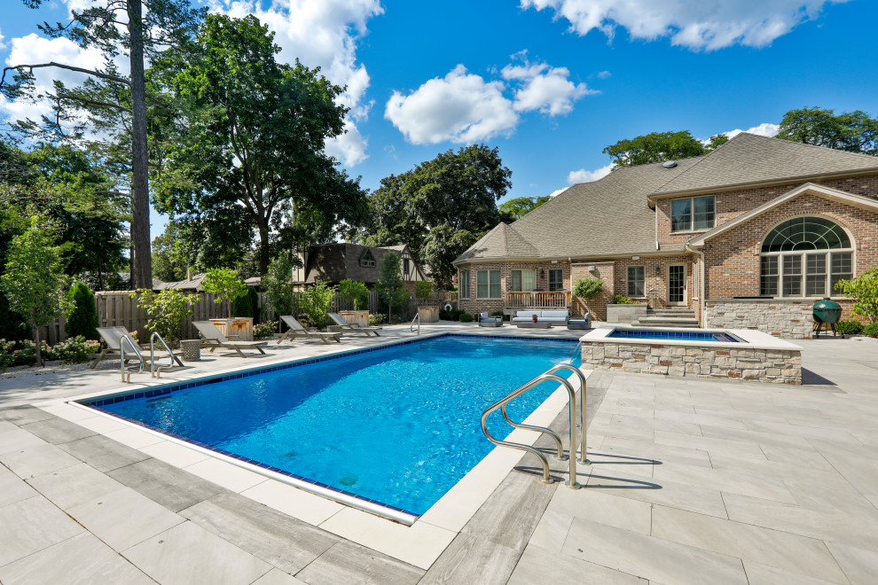 This is an example of a mid-sized traditional backyard rectangular lap pool in Chicago with with a pool and natural stone pavers.