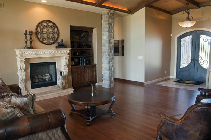 Mid-sized contemporary open concept living room in Wichita with beige walls, medium hardwood floors, a standard fireplace, a plaster fireplace surround and brown floor.