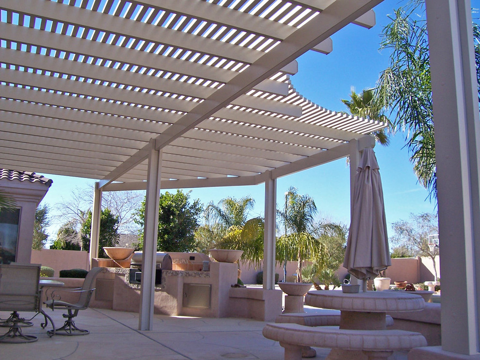 Large tropical backyard patio in Phoenix with an outdoor kitchen, natural stone pavers and a pergola.