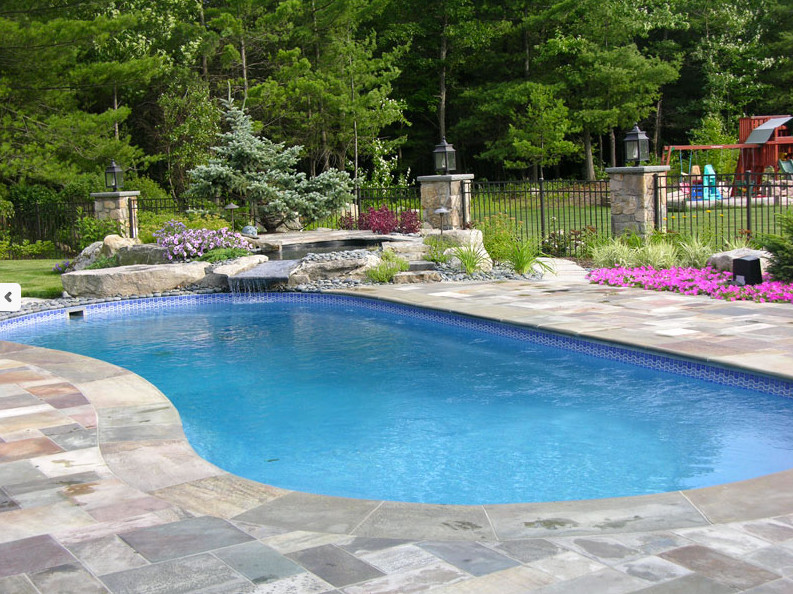 Design ideas for a large contemporary backyard custom-shaped lap pool in St Louis with a water feature and natural stone pavers.