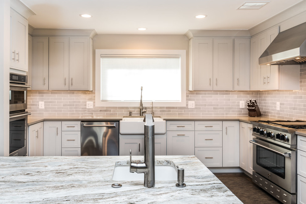 Transitional medium tone wood floor and brown floor eat-in kitchen photo in DC Metro with a farmhouse sink, shaker cabinets, white cabinets, granite countertops, white backsplash, subway tile backsplash, stainless steel appliances, an island and multicolored countertops