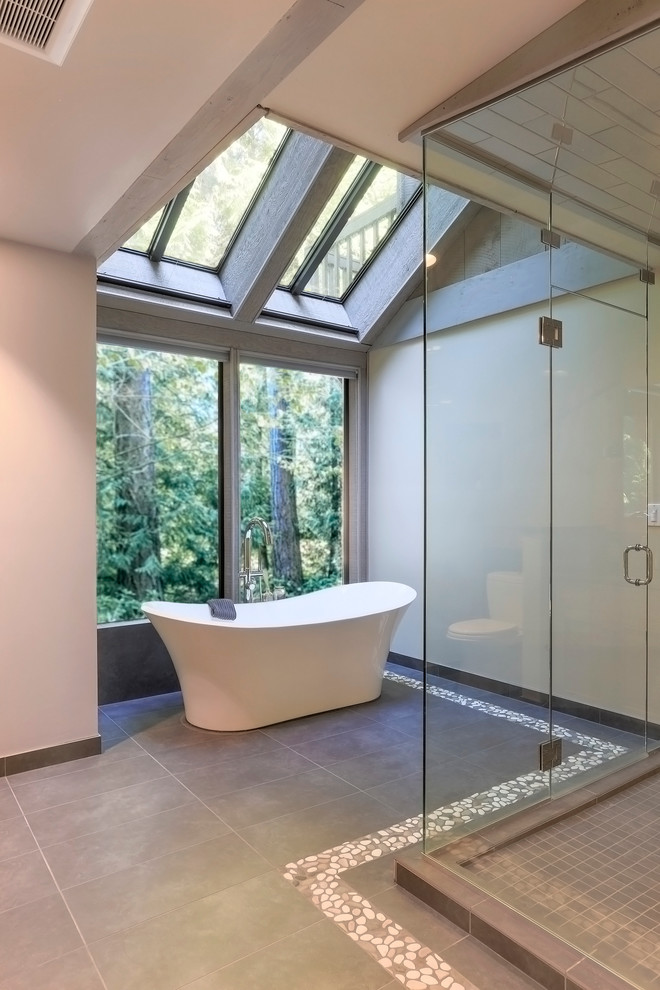 This is an example of a large modern master bathroom in Seattle with shaker cabinets, light wood cabinets, a freestanding tub, a two-piece toilet, gray tile, porcelain tile, beige walls, porcelain floors, an undermount sink and engineered quartz benchtops.