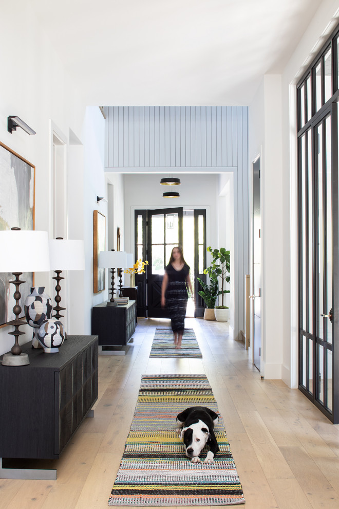 Large contemporary foyer in Los Angeles with white walls, light hardwood flooring, a single front door, a black front door, beige floors, a vaulted ceiling and tongue and groove walls.