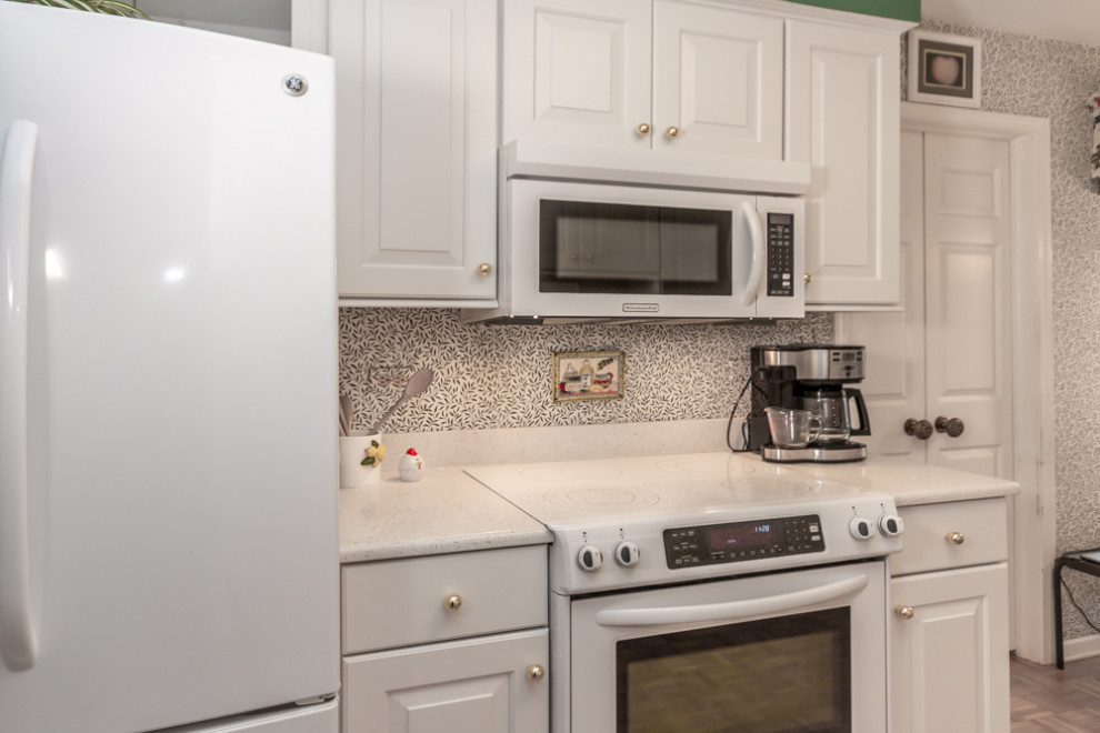 This is an example of a traditional kitchen in Chicago with an undermount sink, raised-panel cabinets, white cabinets, quartz benchtops, white appliances, no island and white benchtop.