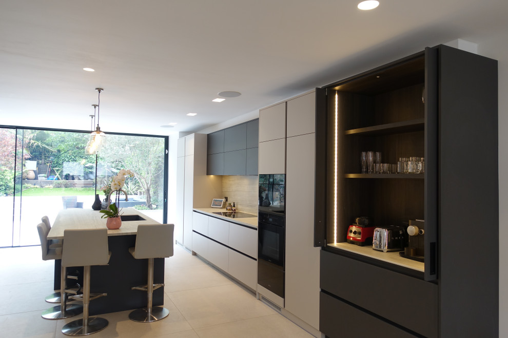Mid-sized modern single-wall eat-in kitchen in London with a drop-in sink, flat-panel cabinets, grey cabinets, solid surface benchtops, white splashback, stone slab splashback, black appliances, porcelain floors, with island, beige floor and white benchtop.