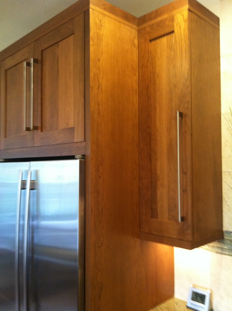 Eat-in kitchen - transitional l-shaped eat-in kitchen idea in Denver with an undermount sink, shaker cabinets, medium tone wood cabinets, beige backsplash, stone tile backsplash and stainless steel appliances