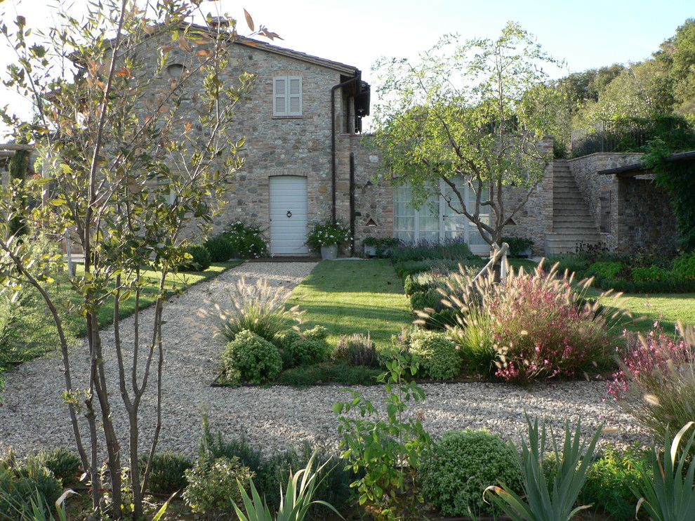 Large country side yard formal garden in Other with gravel.